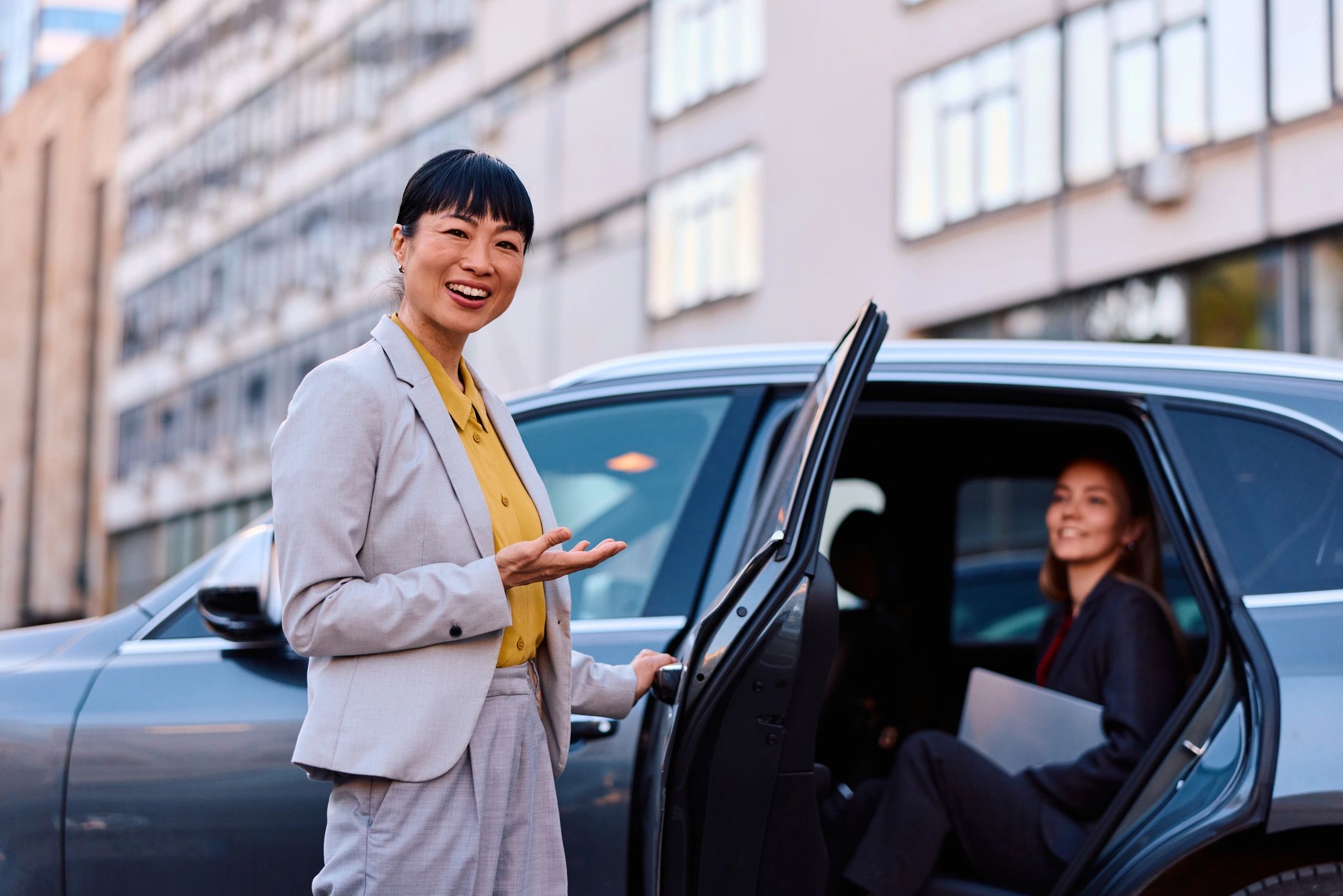Professional chauffeur welcoming client at luxury vehicle